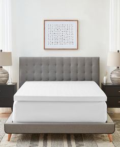 a bed with a gray headboard and white mattress in a room next to two nightstands