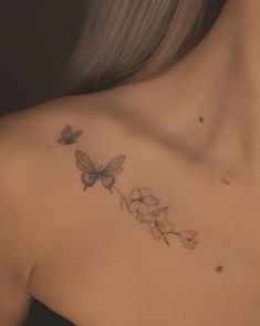 the back of a woman's shoulder with flowers and butterflies tattoo on her chest