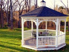 a white gazebo sitting on top of a lush green field