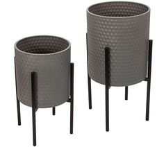 two gray planters sitting next to each other on black metal stands with handles and legs