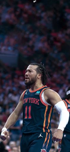 a basketball player with dreadlocks is in the middle of a game and has his hand on his hip