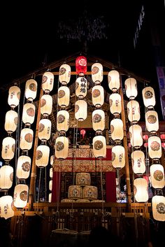 many white paper lanterns are hanging from the ceiling in front of a building at night