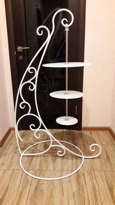 a three tiered cake stand on the floor in front of a door with an iron scroll design