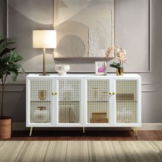 a white sideboard with wicker doors in a living room next to a potted plant