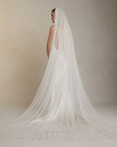 a woman in a wedding dress with a long veil on her head and back view