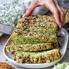 someone is cutting up some bread on a plate with other food items in the background