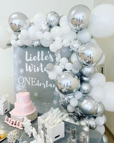 a table with balloons, cake and other items on it for a winter themed birthday party