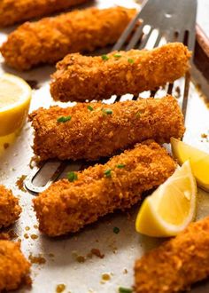 fried fish sticks with lemon wedges on a baking sheet