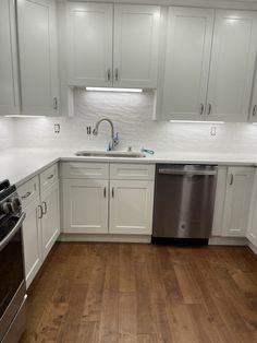 an empty kitchen with white cabinets and wood flooring is seen in this image from the front view