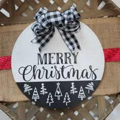 a merry christmas sign is hanging on a basket with burlocks and red ribbon