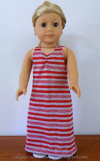 a doll with blonde hair wearing a red and white striped dress on a wooden table