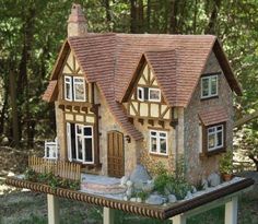 a doll house sitting on top of a table in the middle of some grass and trees