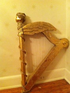 a golden harp sitting on top of a hard wood floor next to a white wall