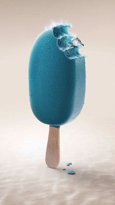 an ice cream popsicle with blue icing on it's tip and some sea foam falling off the top