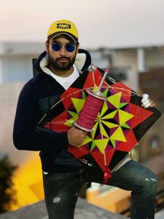 a man holding a colorful kite on top of a roof