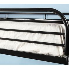 a black metal bed frame with white sheets on top and bottom rails, against a blue wall