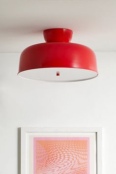 a red light hanging from the ceiling in a white room with pictures on the wall