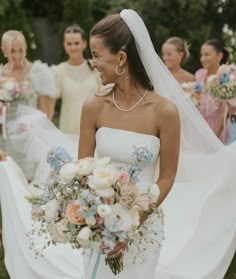 a bride and her bridal party walking down the aisle with their bouquets in hand