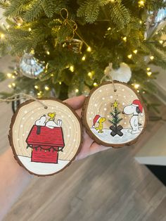 someone holding two ornaments in front of a christmas tree