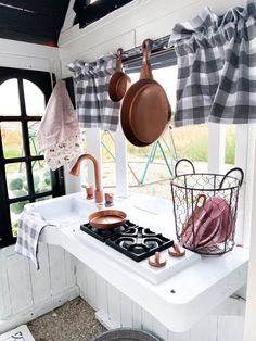 pots and pans are hanging on the window sill in this country kitchen with black and white checkered curtains