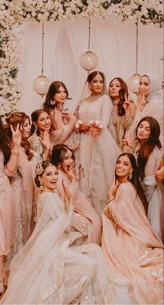 a group of brides posing for a photo in front of a flower covered wall