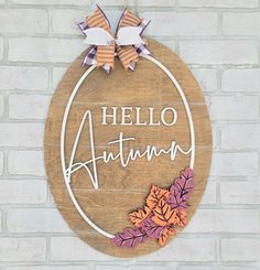 a wooden sign hanging on the side of a brick wall that says, hello autumn