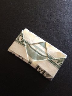 an origami piece of paper folded in one dollar bill on a black surface