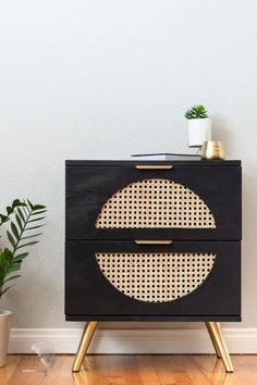 a black and gold cabinet with a potted plant next to it on a wooden floor