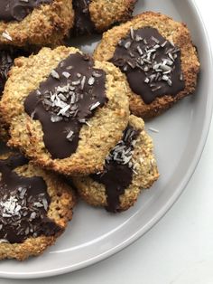 chocolate covered cookies on a white plate with sprinkles and coconut flakes