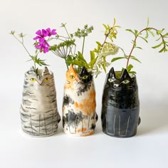 three ceramic vases with flowers in them