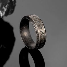 a silver ring with the word love written on it, sitting next to a rock