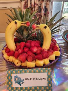 two birds made out of strawberries and bananas on a plate with a name tag