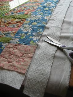 a pair of scissors sitting on top of a table next to a piece of cloth