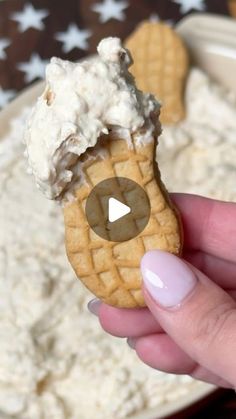 a person holding an ice cream cone in front of a bowl full of whipped cream