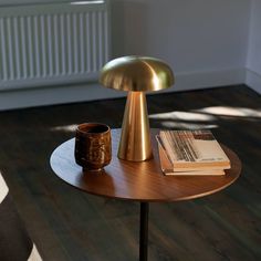 a wooden table with a gold lamp on top and a coffee cup sitting on it