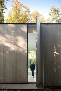 a woman is walking through the open door to her home, which has wood panels on both sides