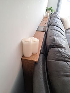 two candles are sitting on a wooden shelf next to a couch in a living room