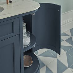 an open cabinet in the middle of a kitchen with blue and white tile flooring