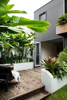 a wooden deck with plants on it next to a building