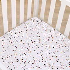 a white crib bed with multicolored dots on it