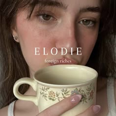 a woman is holding a coffee cup in her right hand with the words elodie on it