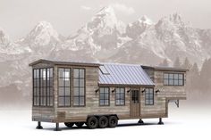 a tiny house on wheels with mountains in the background