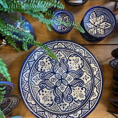 a blue and white plate sitting on top of a wooden table next to green plants