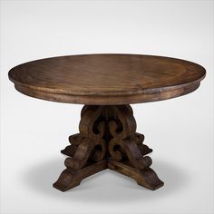 a round wooden table with an intricate design on the top and base, sitting against a white background