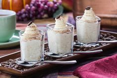 three desserts with whipped cream and chocolate chips on a tray next to a cup of coffee