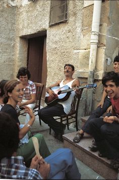 a group of people sitting around each other on steps with guitars in their hands and one man playing the guitar