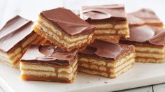 several pieces of cake sitting on top of a white cutting board with chocolate frosting