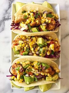 three tacos on a plate with corn and avocado