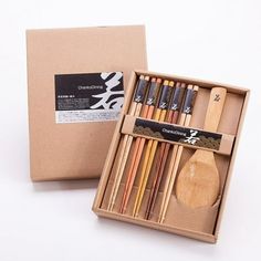 an open box filled with different colored pencils and wooden utensils in it