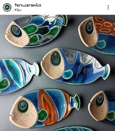 five colorful fish shaped plates sitting on top of a gray tablecloth covered countertop